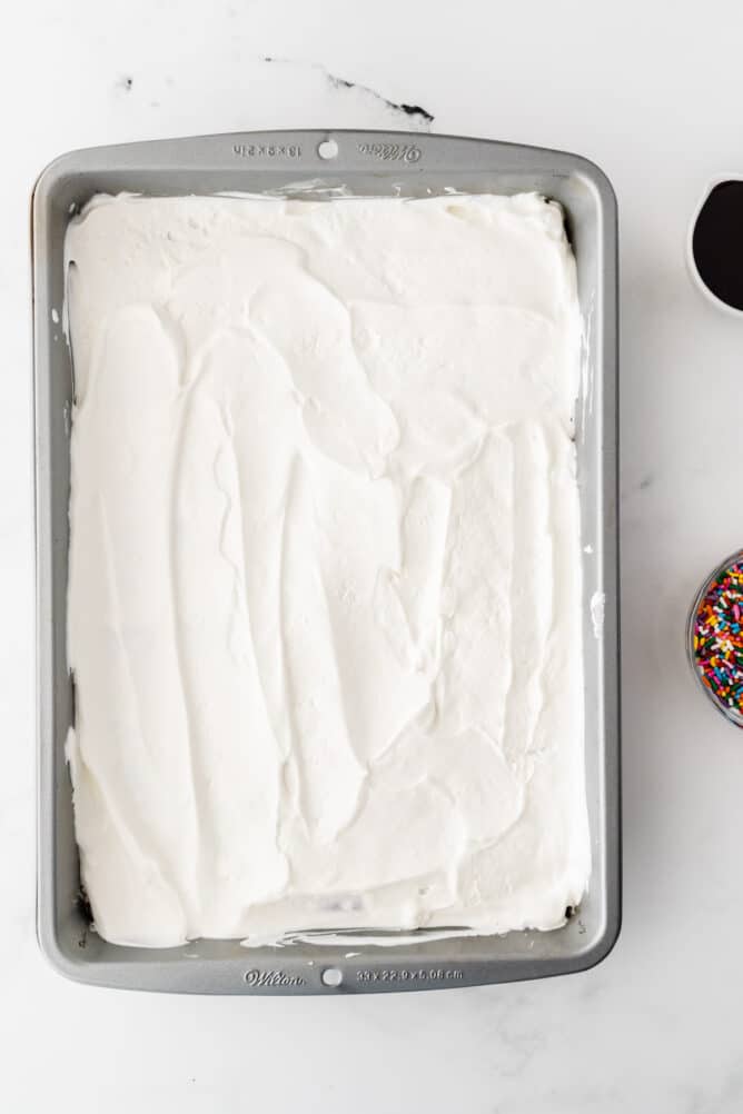 Overhead process shot showing whipped topping covering ice cream sandwiches