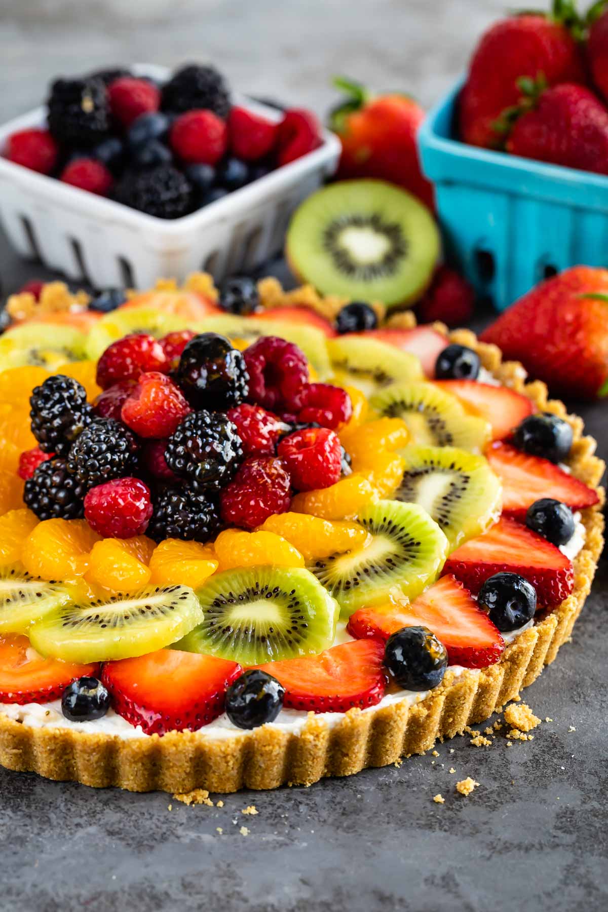 Side shot of no bake fruit tart with lots of fruit in the background