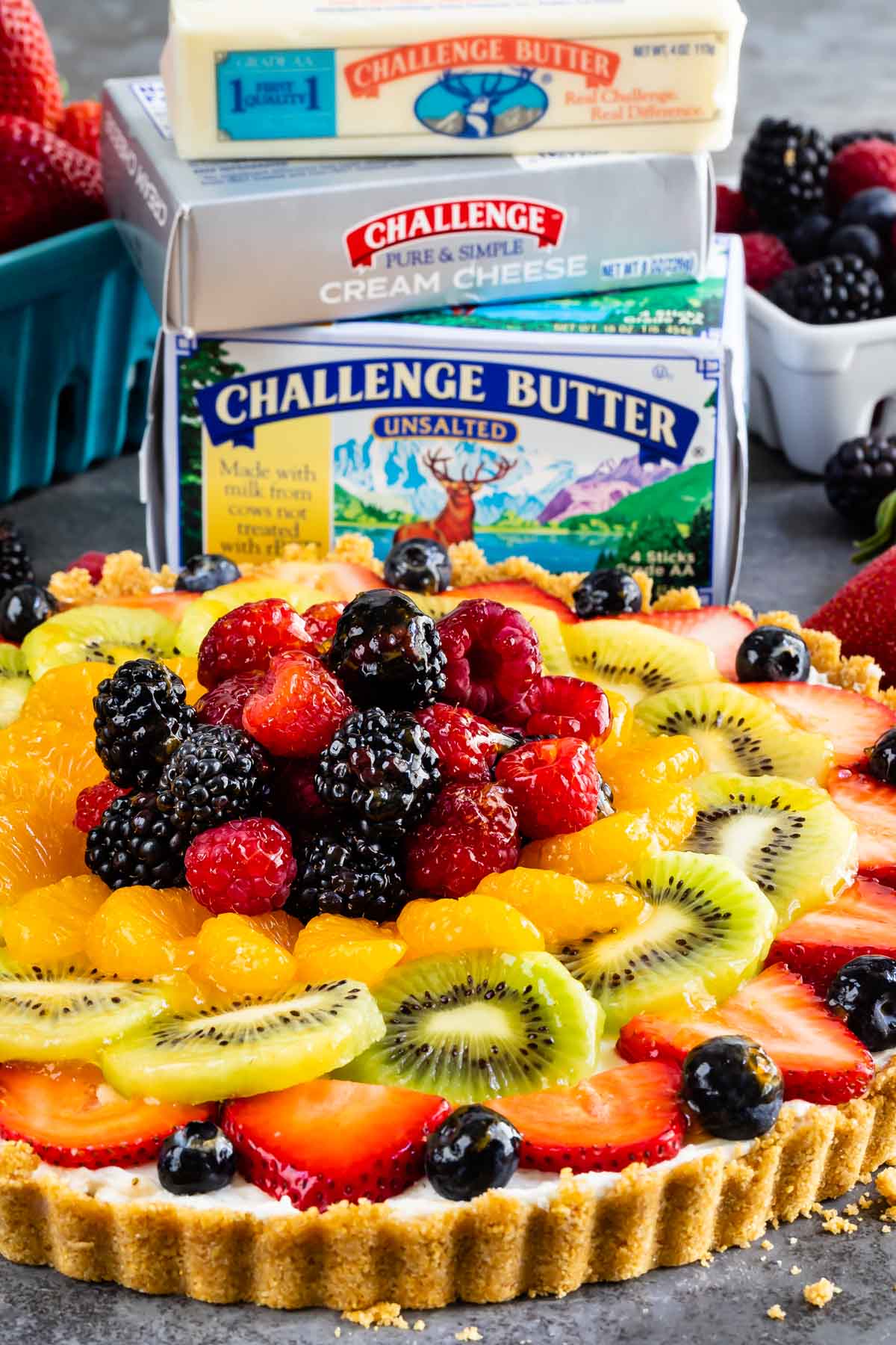 Side shot of no bake fruit tart with challenge butter and cream cheese in background