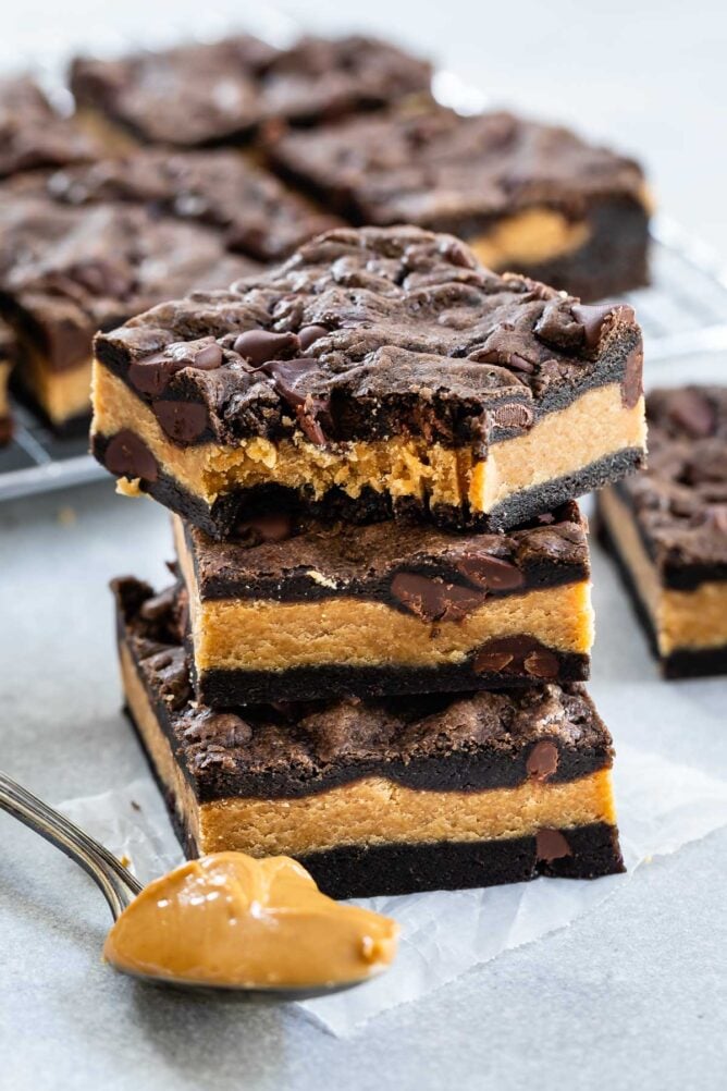 Stack of peanut butter stuffed chocolate cookie bars with the top bar missing one bite