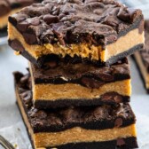 Stack of peanut butter stuffed chocolate cookie bars with the top bar missing one bite
