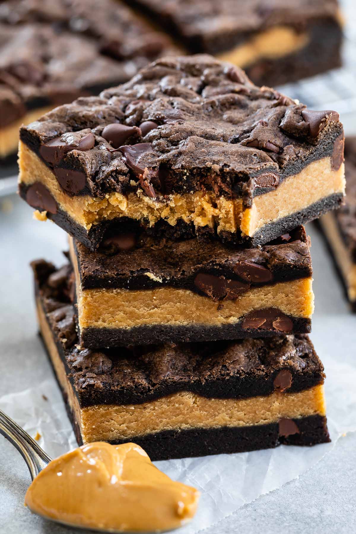 Stack of peanut butter stuffed chocolate cookie bars with the top bar missing one bite