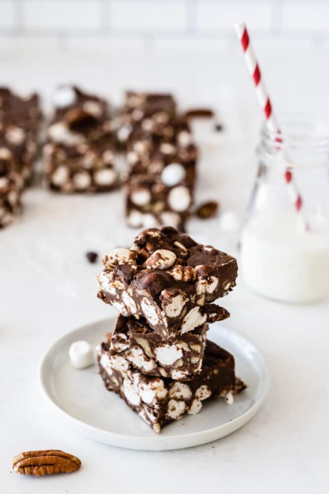 Three easy rocky road bars stacked on eachother with a glass of milk in the background