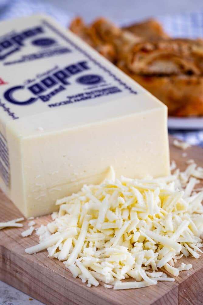 block of Cooper cheese with shredded cheese in front