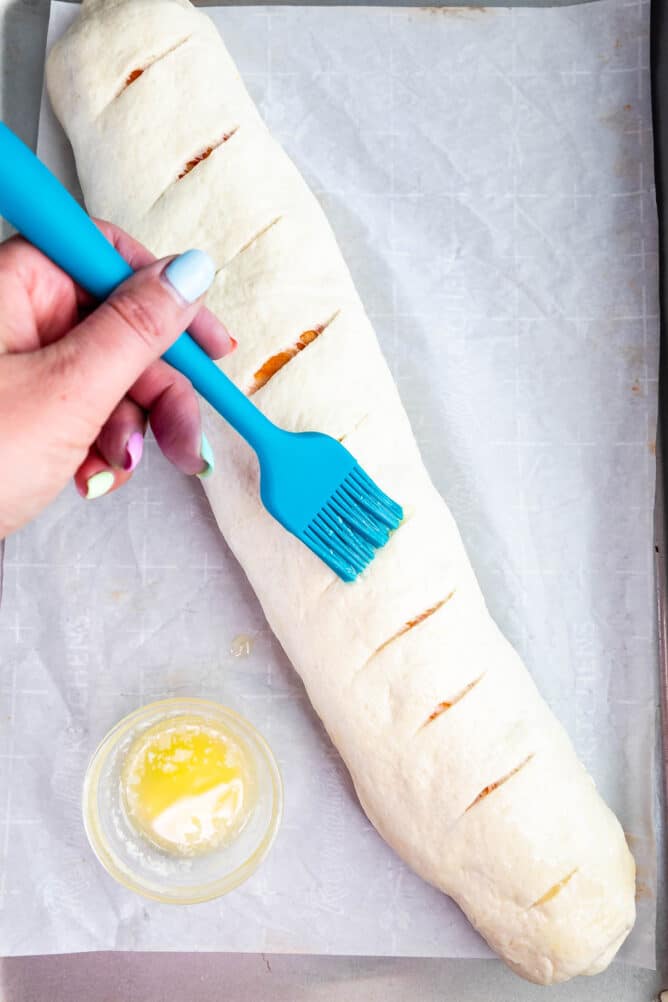 hand brushing butter over Stromboli