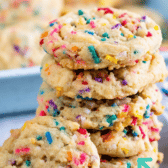 Tall stack of cake batter cookies with sprinkles around them and recipe title on top of image