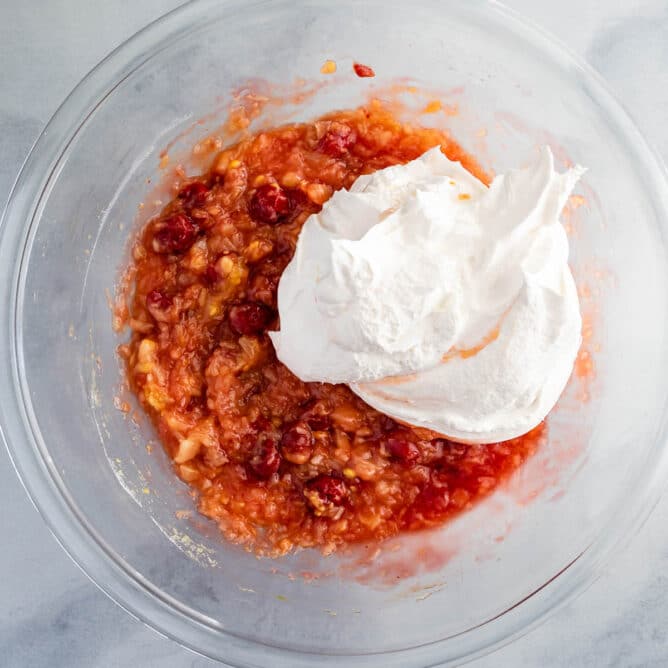 Overhead shot showing cool whip being mixed into bowl with other ingredients