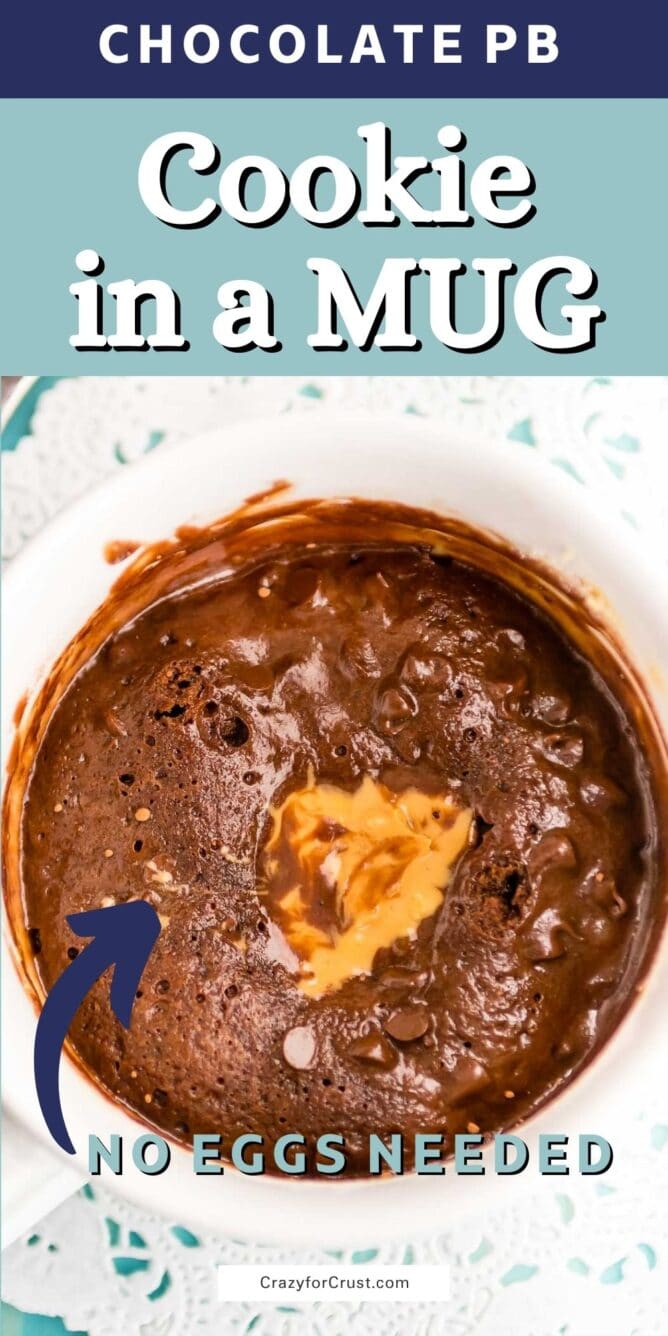 overhead shot of chocolate cookie in a white mug with peanut butter on top of a doilies and blue background