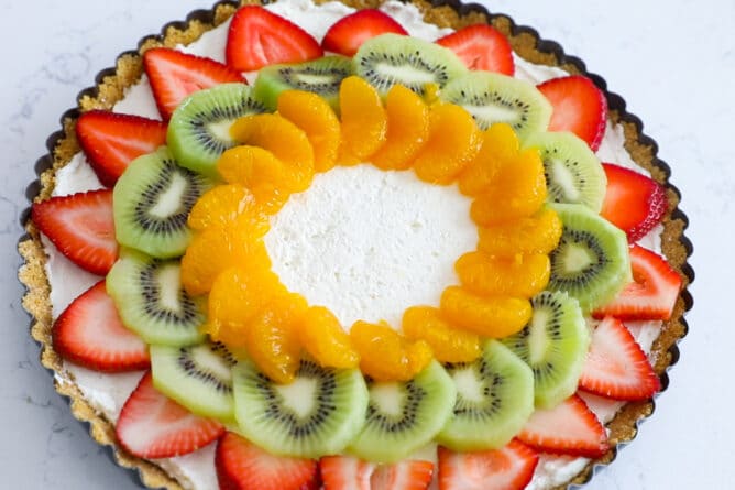 No bake fruit tart topped with strawberries, kiwis and oranges