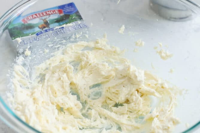 Clear mixing bowl with the start of the cream cheese filling with challenge cream cheese in background