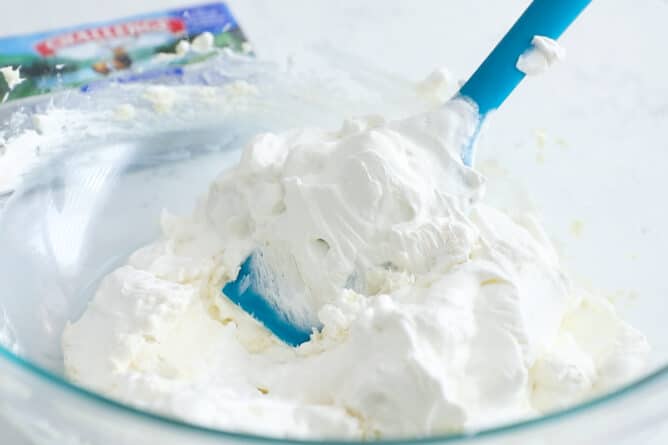 Cream cheese filling being stirred in a glass mixing bowl