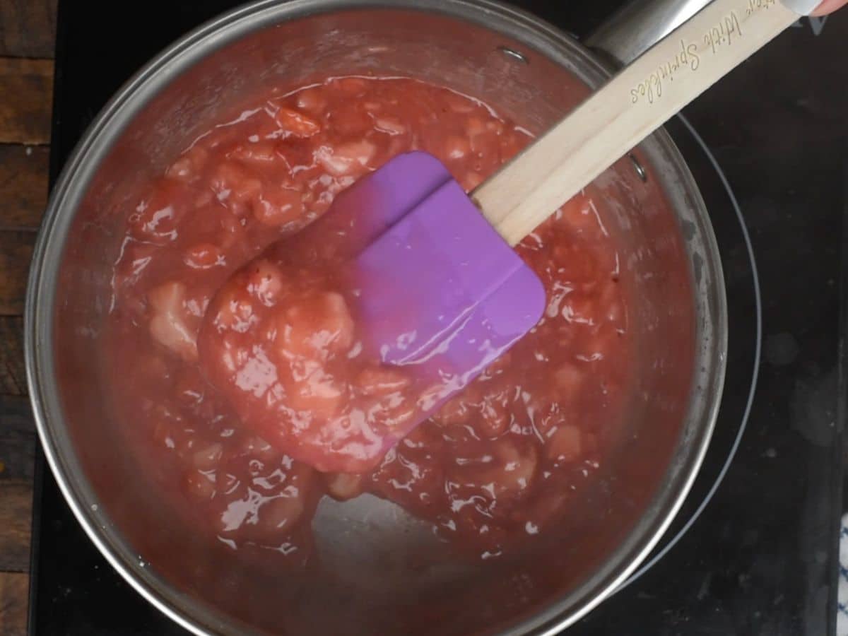 thickened strawberry mixture in saucepan with spatula.