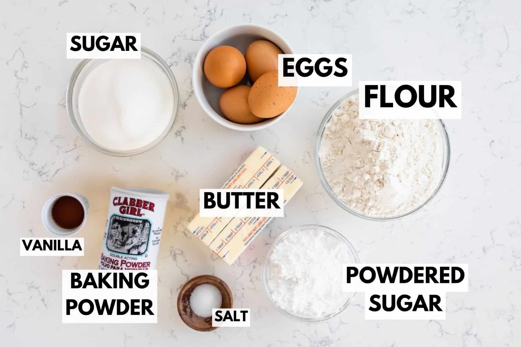 Top-down view of baking ingredients for waffle cookies on a white surface, each labeled: sugar, eggs, flour, vanilla, baking powder, butter, salt, and powdered sugar in separate bowls and packaging.