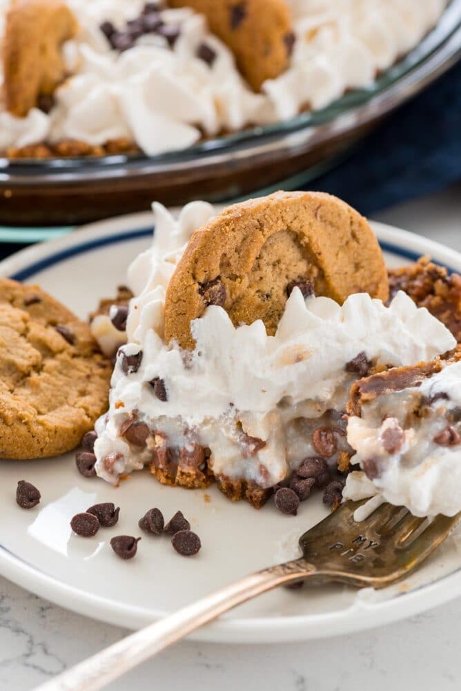 One slice of no bake chocolate chip cookie pudding pie on a plate with one bite on the fork