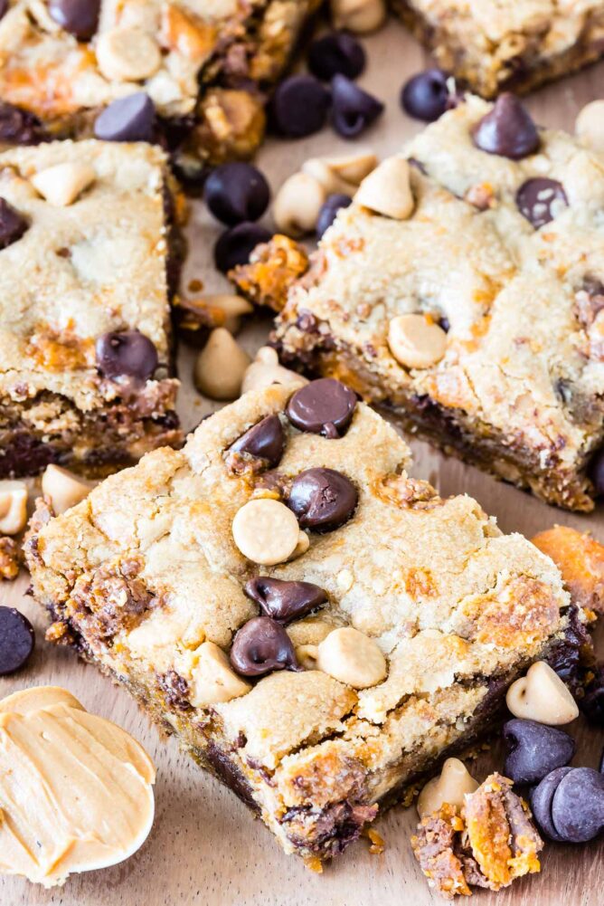 Peanut butter cookie bars cut into squares with mix-ins all around