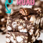 Three easy rocky road bars stacked on eachother with more in the background and recipe title on top of image