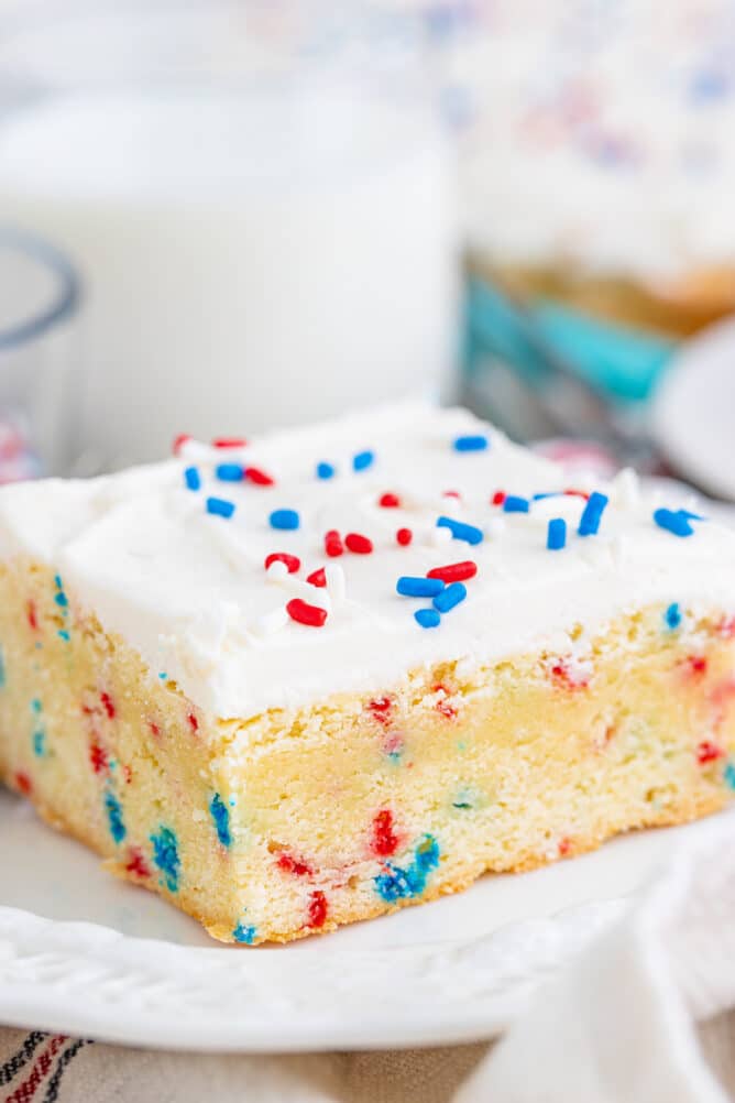 cookie bar with frosting and sprinkles on white plate