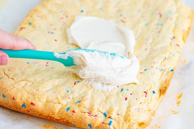 frosting on top of cookie bars with sprinkles