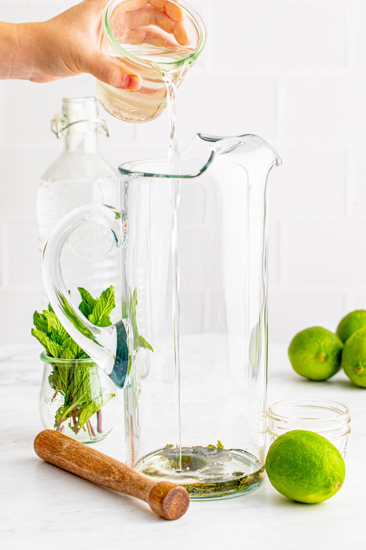 pitcher with hand pouring in liquid.