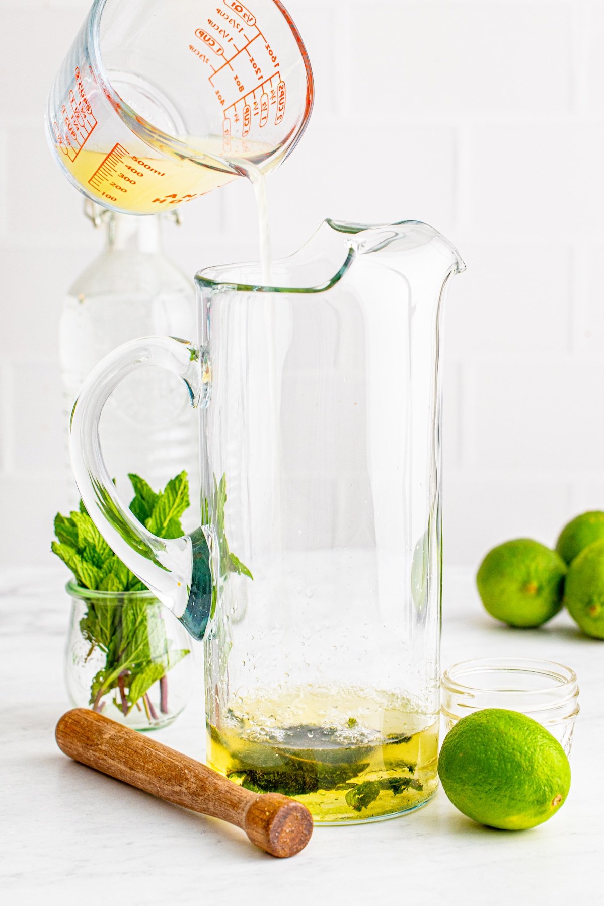 pitcher with hand pouring in liquid.