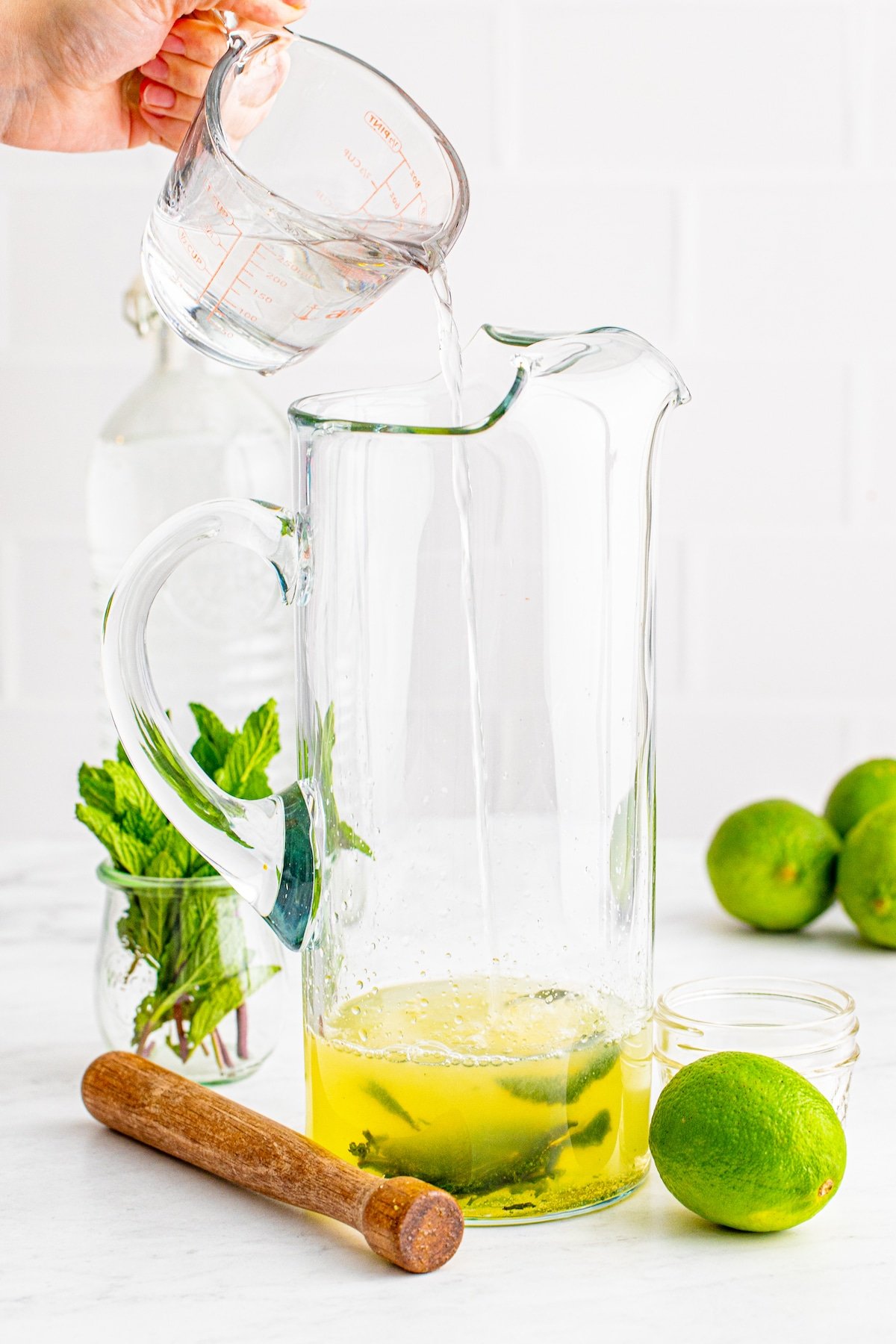 pitcher with hand pouring in liquid.