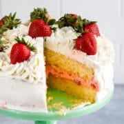 cake with slice missing showing yellow cake and pink filling inside on mint cake plate