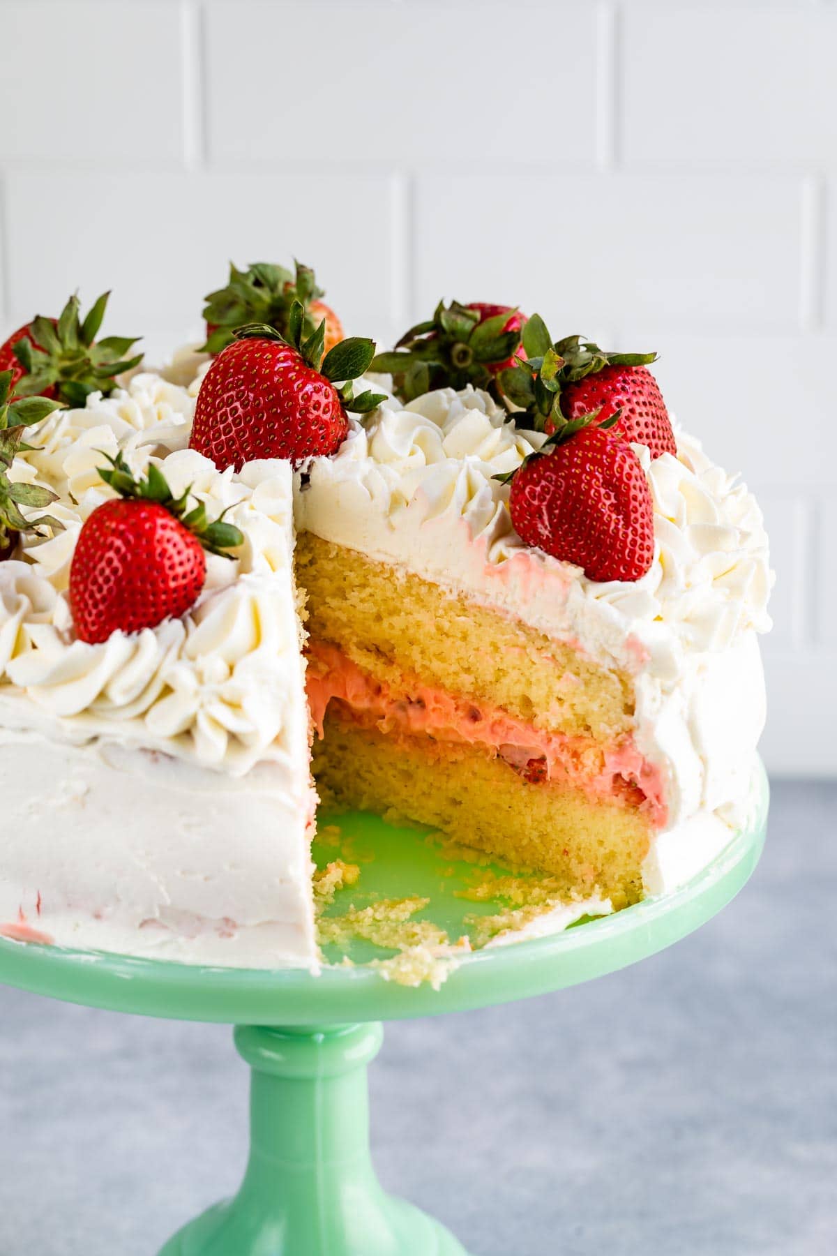 cake with slice missing showing yellow cake and pink filling inside on mint cake plate