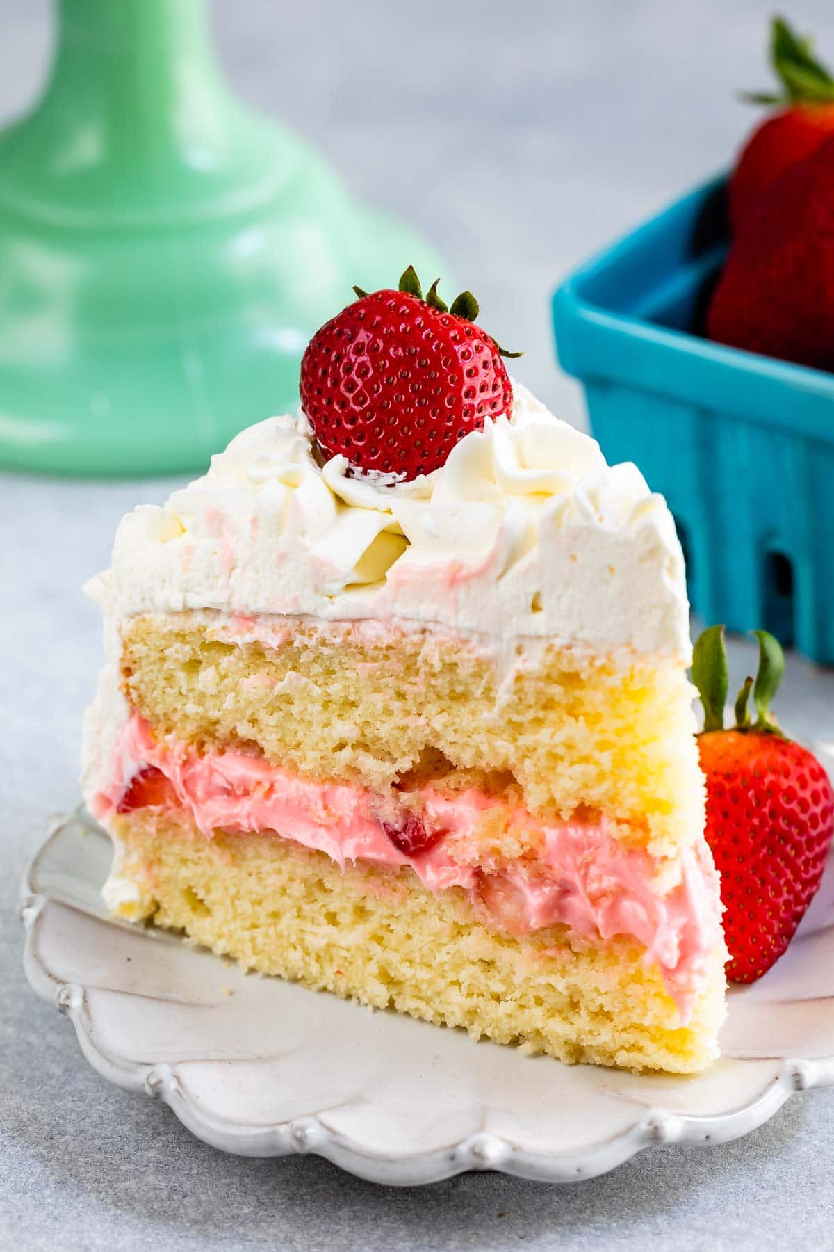 slice of strawberry shortcake layer cake on white plate with fresh berries on top