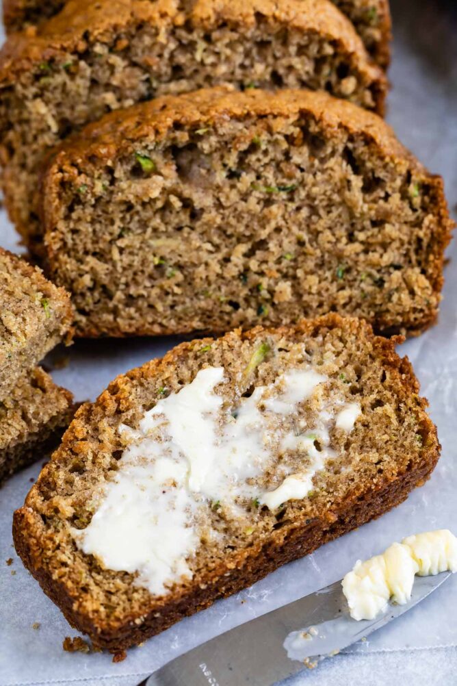 Slices of zucchini bread and front slice is lathered with butter