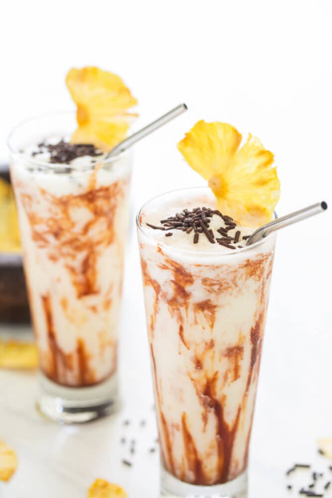 Two chocolate colada drinks with pineapple slices on top