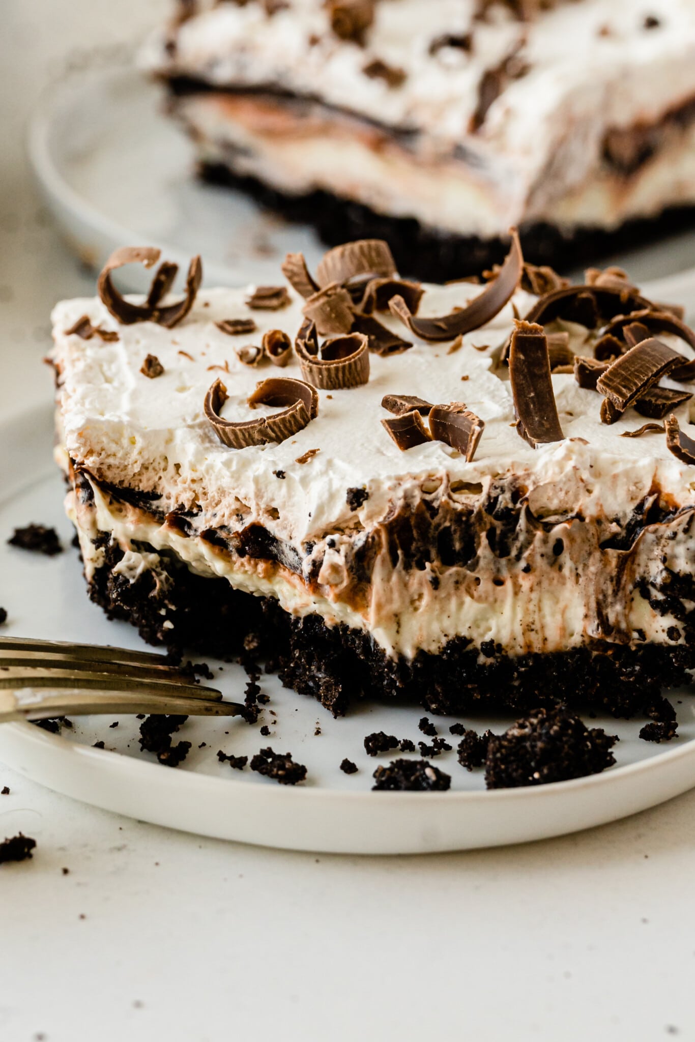 Slice of chocolate lasagna on plate with one bite missing