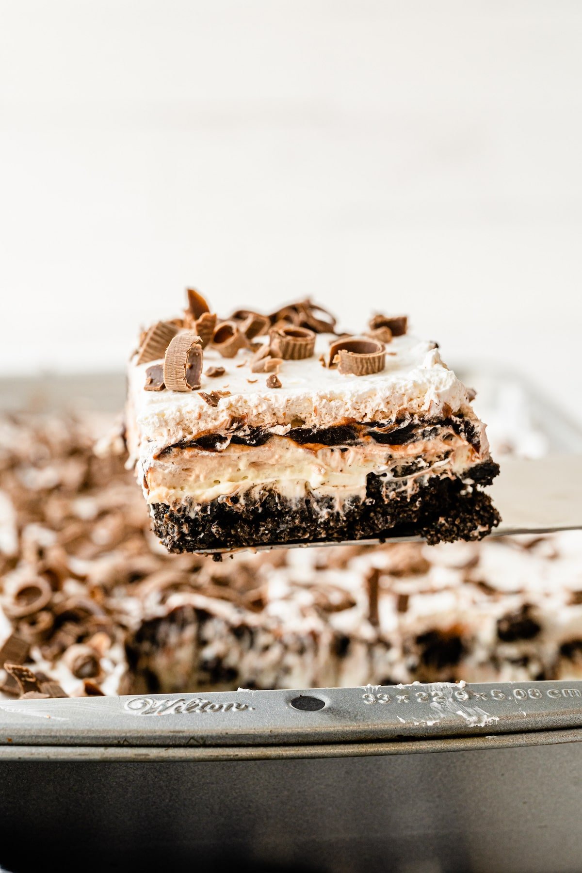 One piece of chocolate lasagna on spatula above the whole dessert