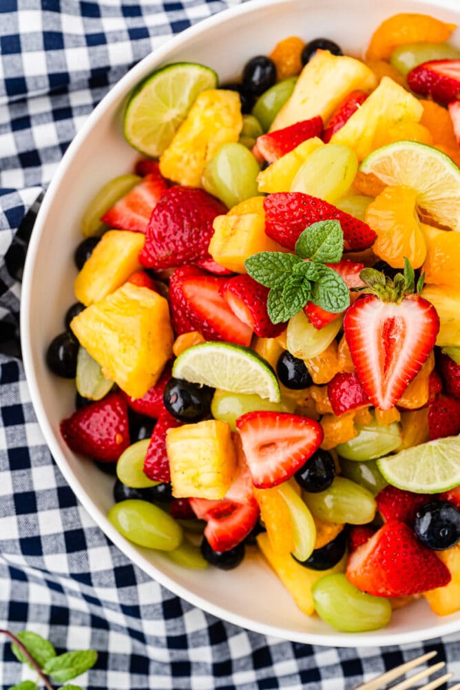 Overhead shot of big bowl of fruit salad on top of a checkered tablecloth