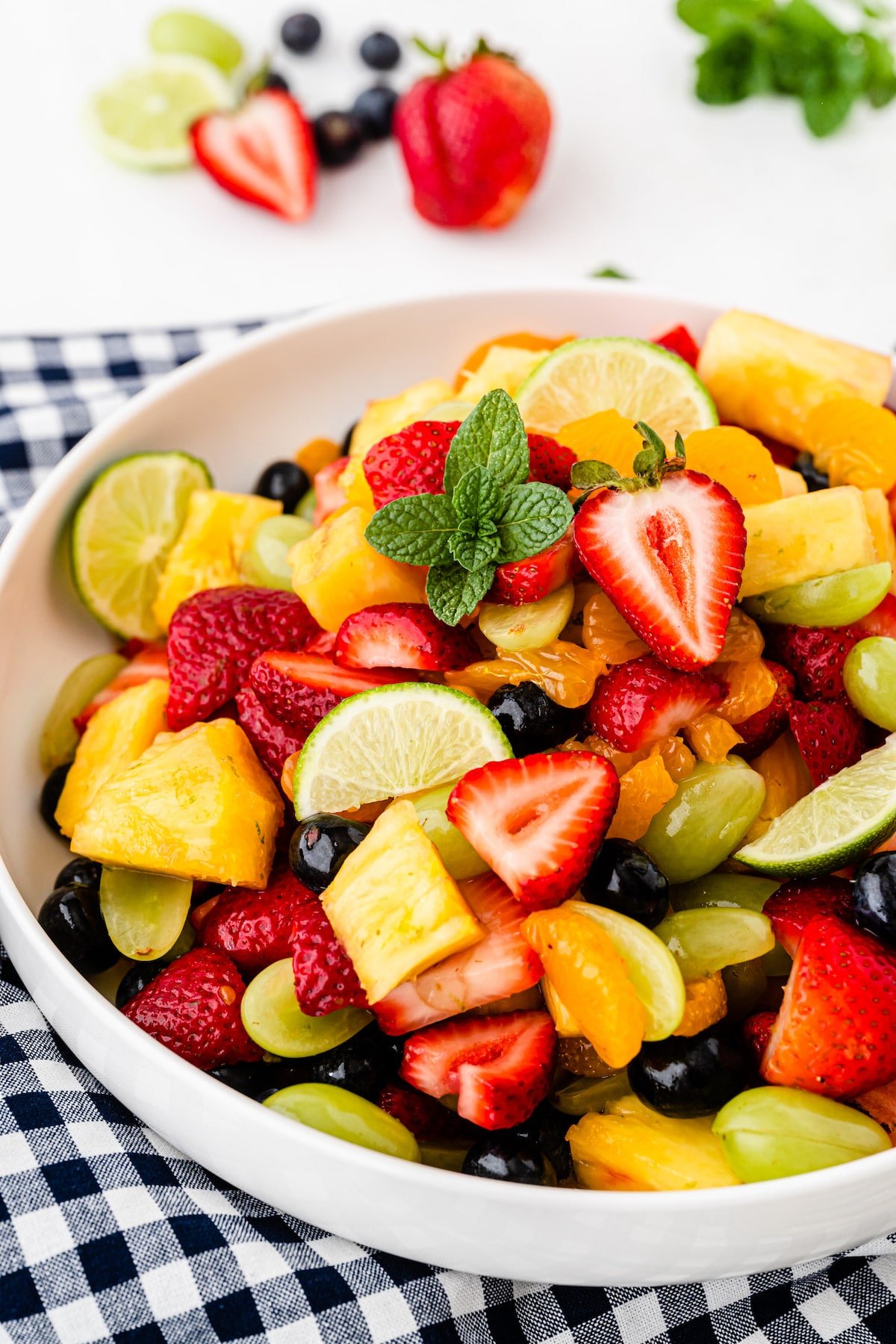 Big bowl of fruit salad on top of a checkered tablecloth