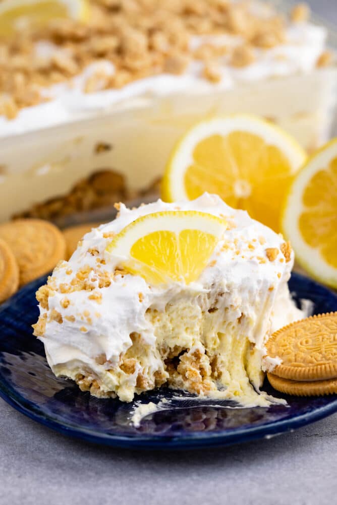 One slice of no bake lemon dessert on blue plate with one bite missing