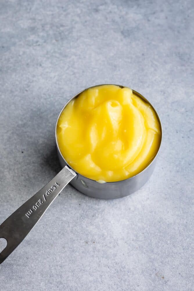 One stainless steel measuring cup full of lemon curd