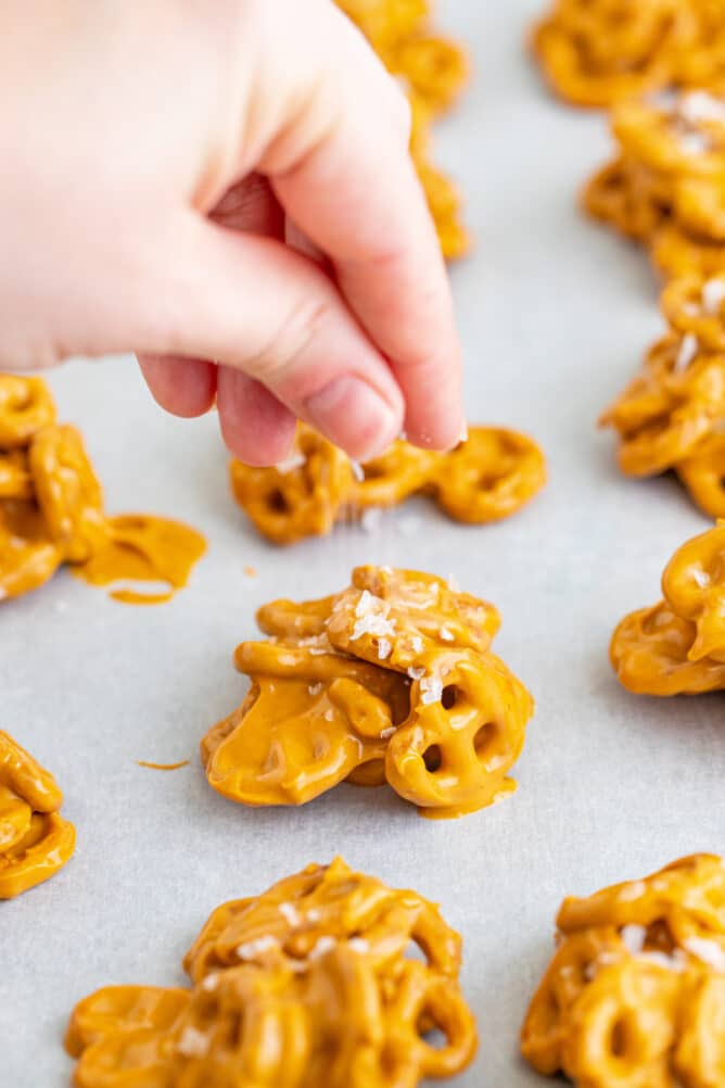 Close up shot of sea salt being sprinkled on top of no bake pretzel cookie