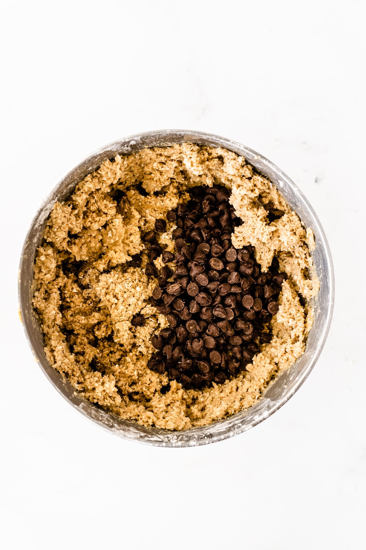 cookie dough in mixer bowl with chocolate chips.