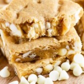Stack of white chocolate blondies with top blondie missing a bite