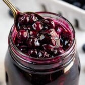 Blueberry pie filling in a small mason jar with spoon coming out of it