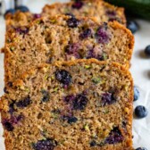 Three slices of blueberry zucchini bread with blueberries around it