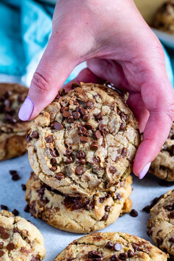 A hand holding up a bakery style chocolate chip cookie