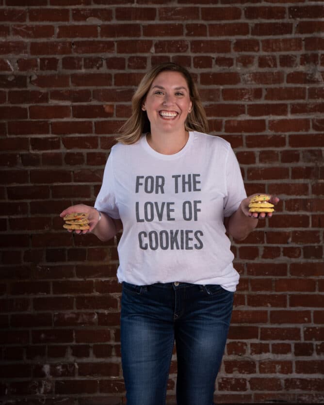woman in white shirt holding cookies in each hand