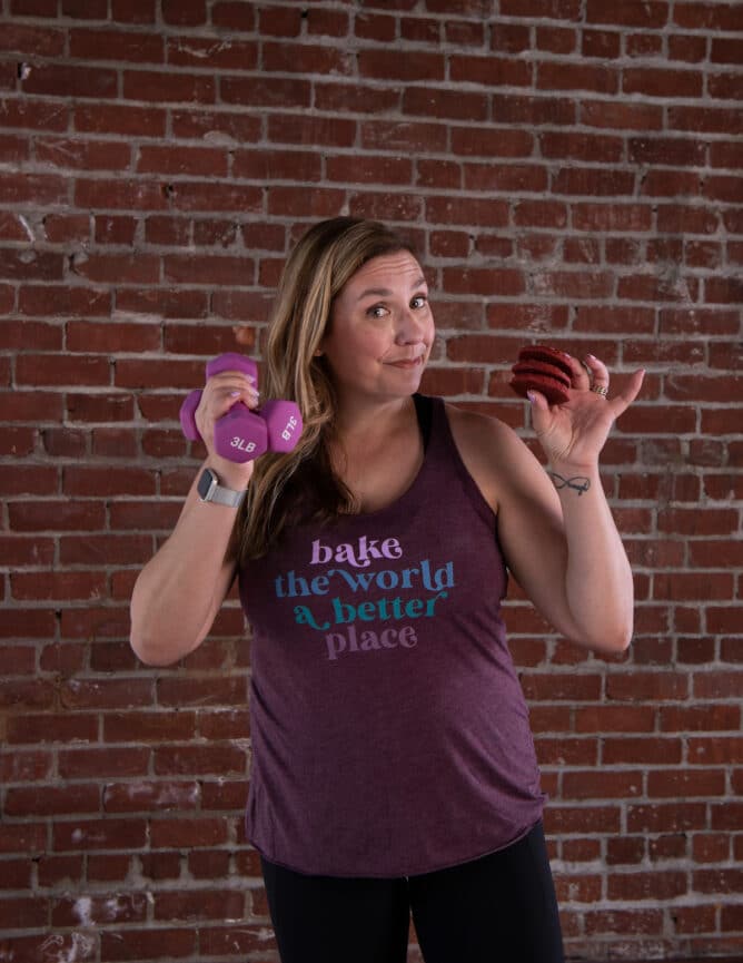 woman in purple tank holding cookies and weights