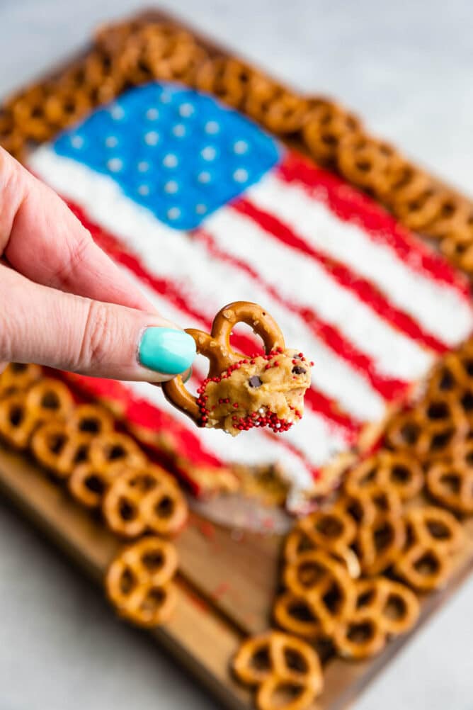 Hand holding a pretzel dipped in the peanut butter flag dip