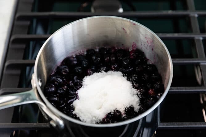 Saucepan full of blueberries, water and sugar on top