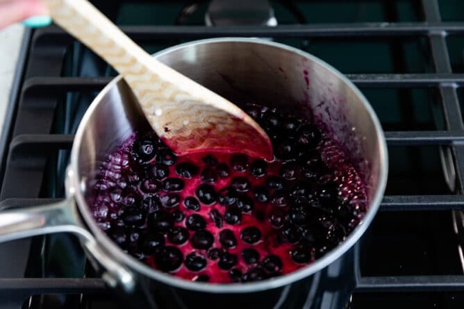 Process shot of blueberry pie filling being stirred in saucepan