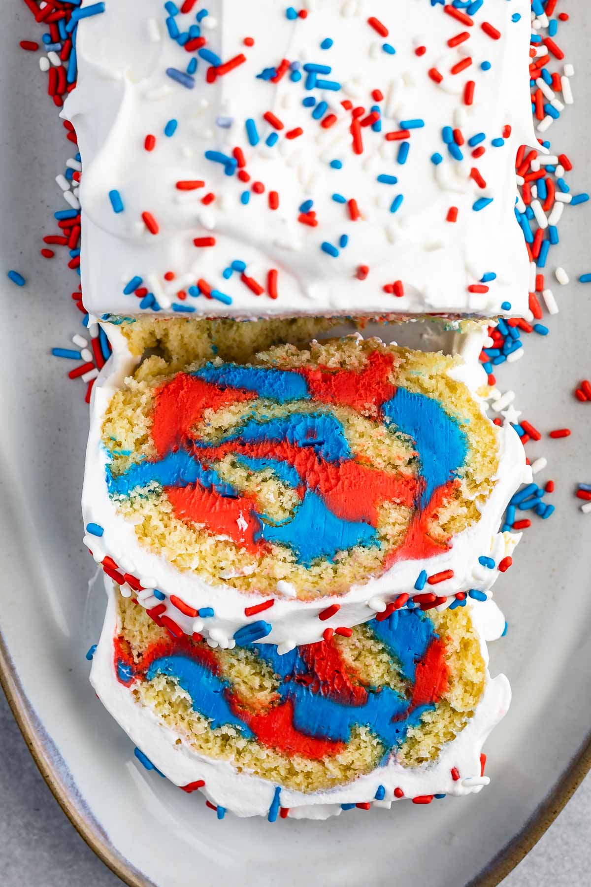 Overhead shot of patriotic cake roll with two pieces sliced into so you can see the inside