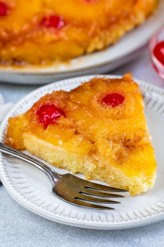 One slice of pineapple upside down cake on a plate with fork