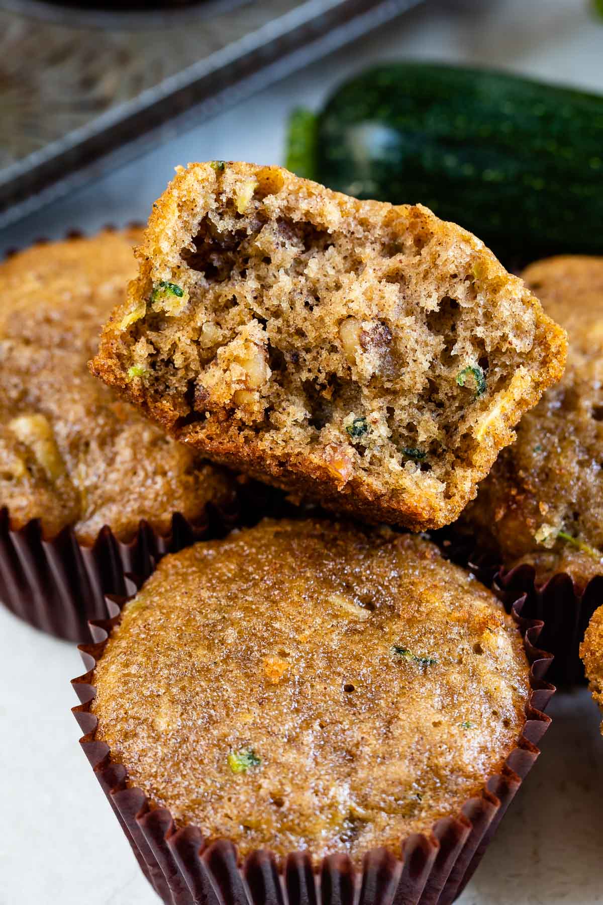 Zucchini muffins with top one split in half to show inside of muffin
